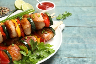 Photo of Delicious chicken shish kebabs with vegetables and parsley on light blue wooden table, closeup. Space for text
