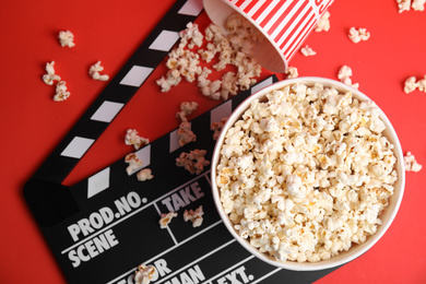 Photo of Tasty pop corn and clapboard on red background, flat lay