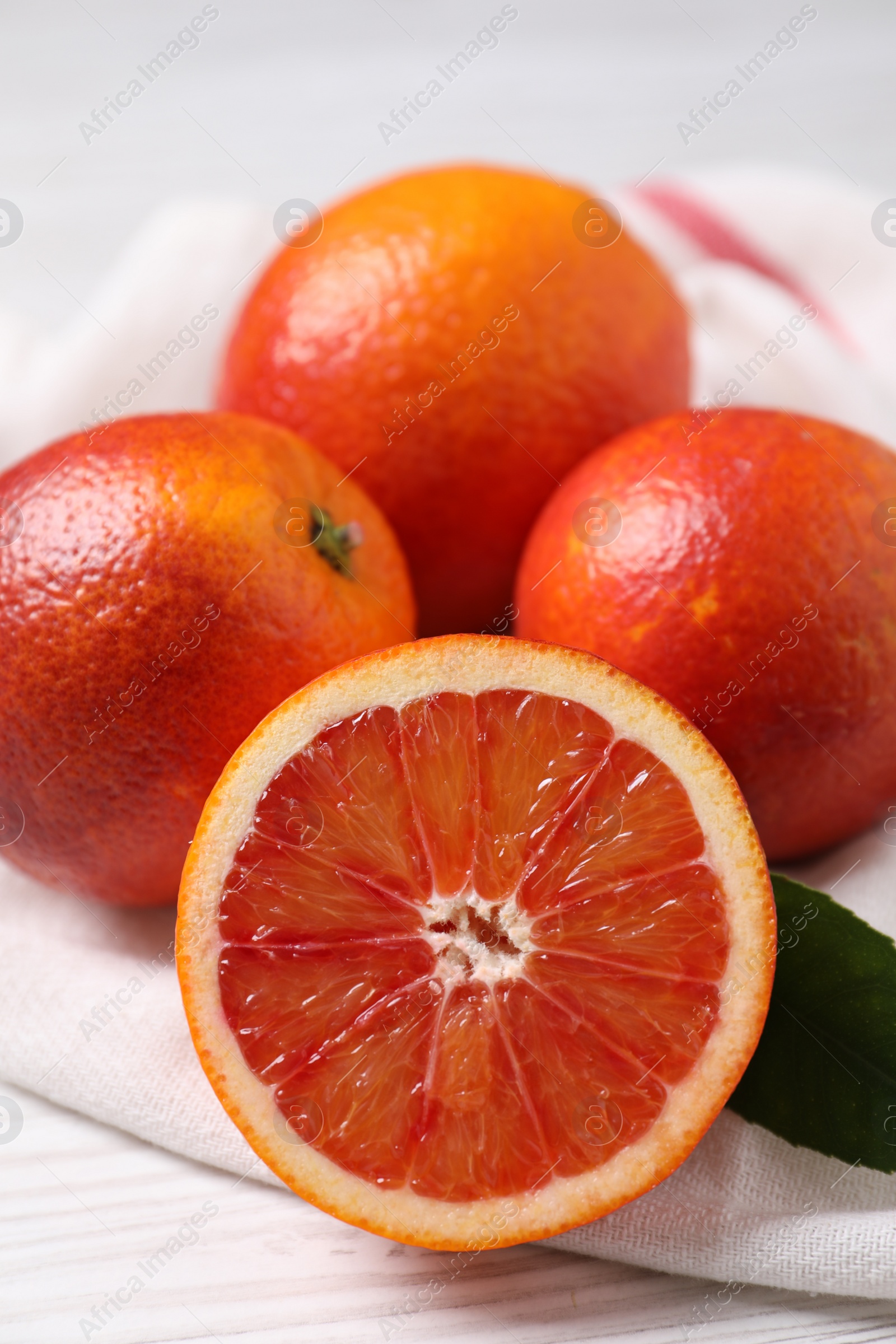 Photo of Whole and cut red oranges on white wooden table, closeup