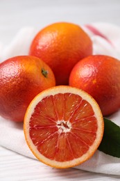 Whole and cut red oranges on white wooden table, closeup