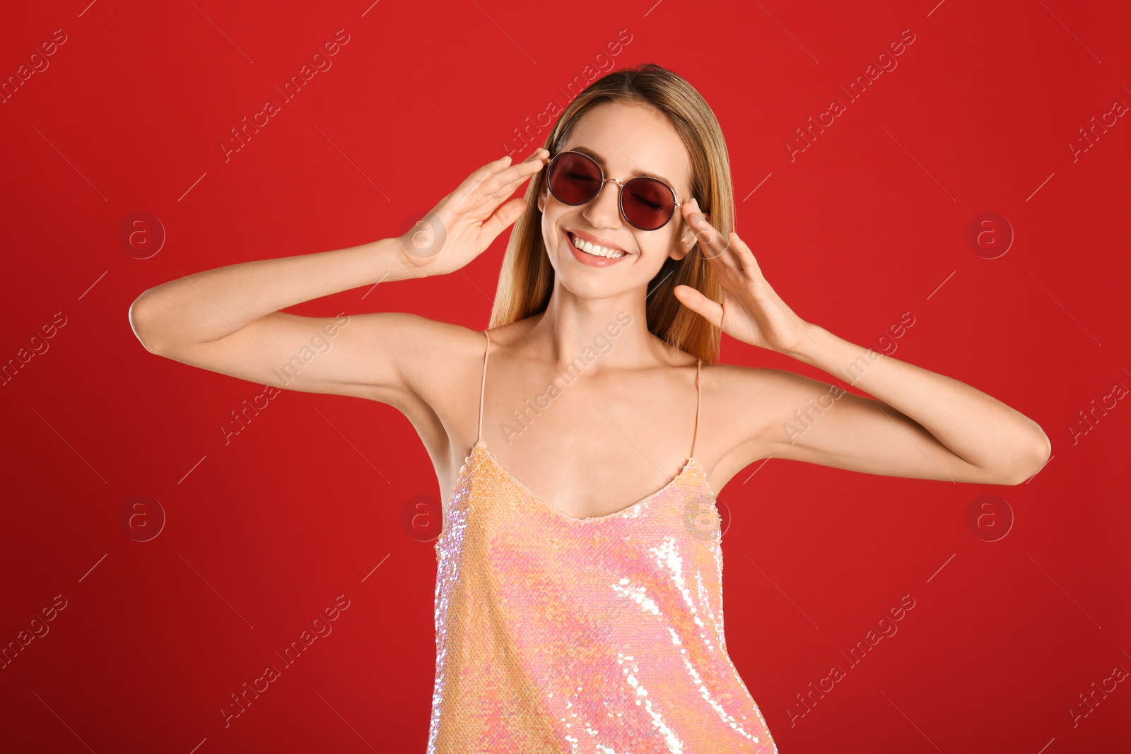 Photo of Beautiful woman in stylish sunglasses on red background