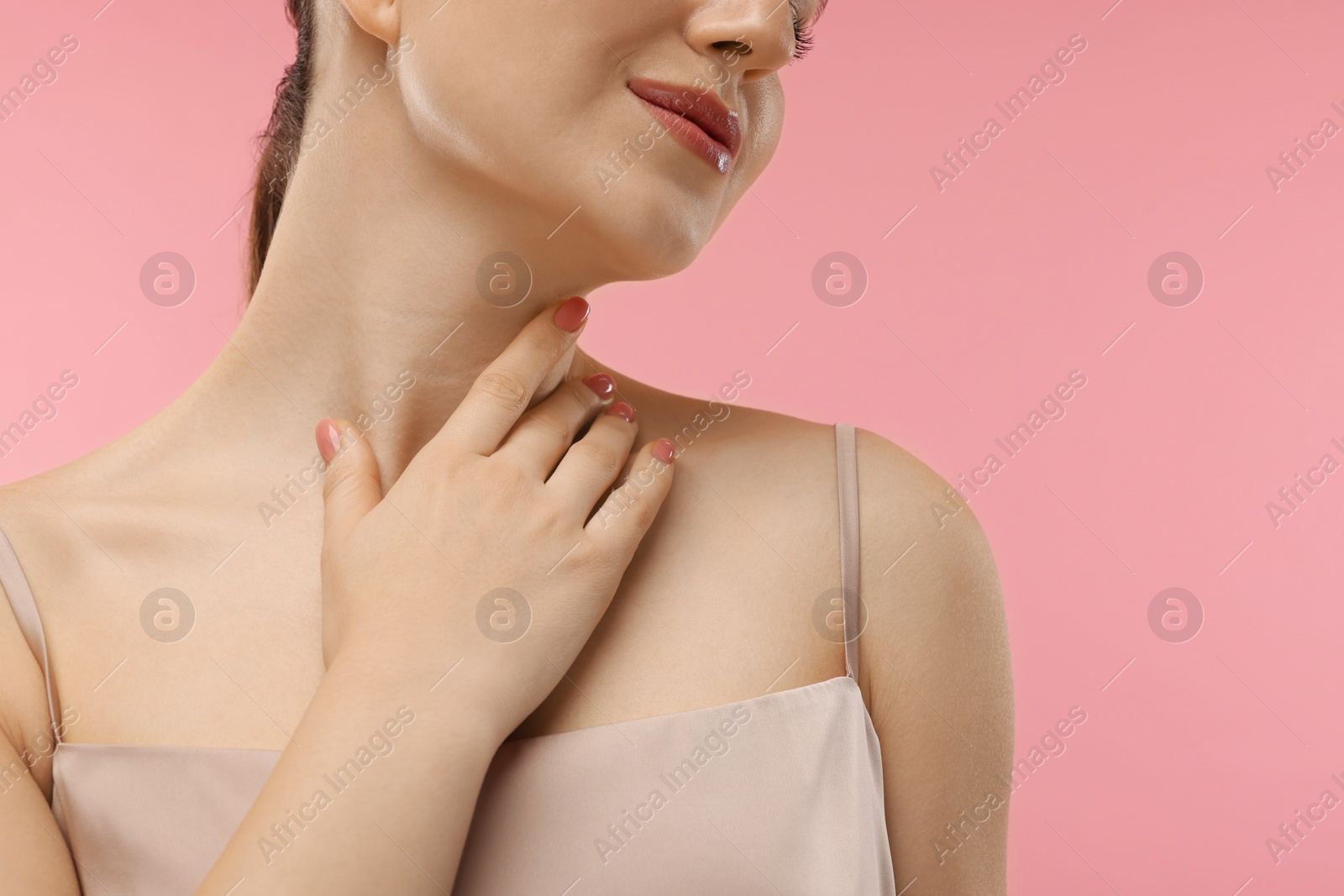 Photo of Woman touching her neck on pink background, closeup