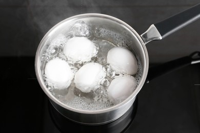 Photo of Chicken eggs boiling in saucepan on electric stove, above view