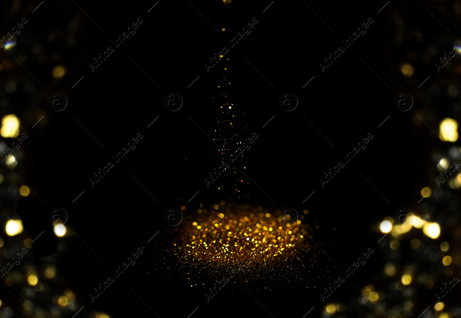Photo of Sprinkling gold glitter on black background, bokeh effect