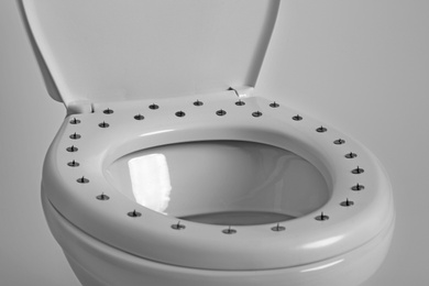 Photo of Toilet bowl with pins on white background, closeup. Hemorrhoids concept