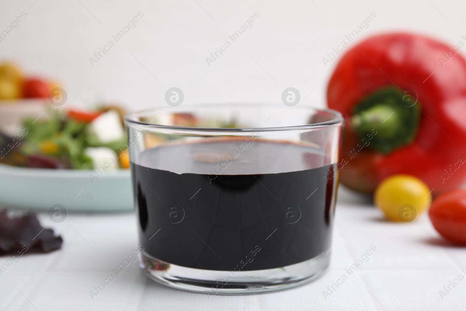 Photo of Vinegar in glass on white tiled table, closeup