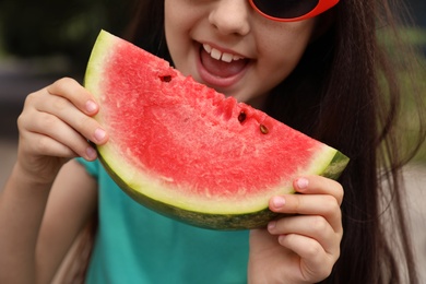 Photo of Cute little girl with watermelon outdoors, closeup