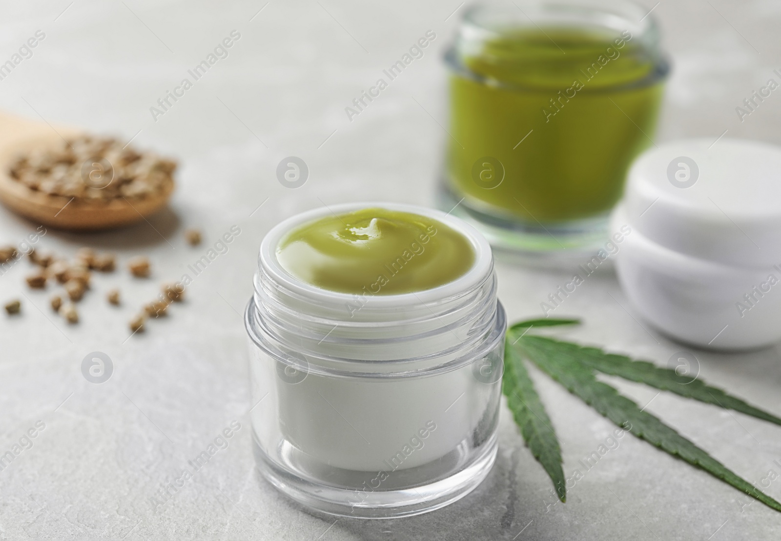 Photo of Jars of hemp cream and seeds on grey table. Organic cosmetics