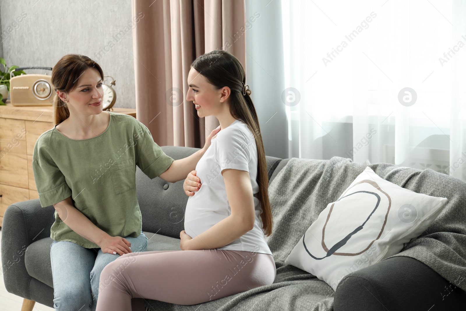 Photo of Doula taking care of pregnant woman on sofa at home. Preparation for child birth