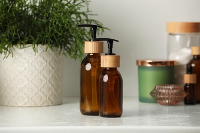 Photo of Bottles with dispenser caps and cosmetic products on white table