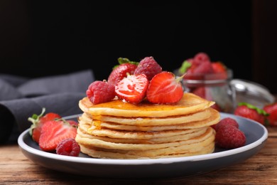 Photo of Tasty pancakes with fresh berries and honey on wooden table, closeup