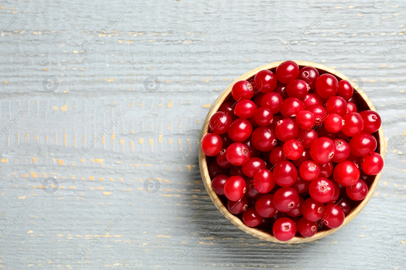 Photo of Tasty ripe cranberries on grey wooden table, top view. Space for text