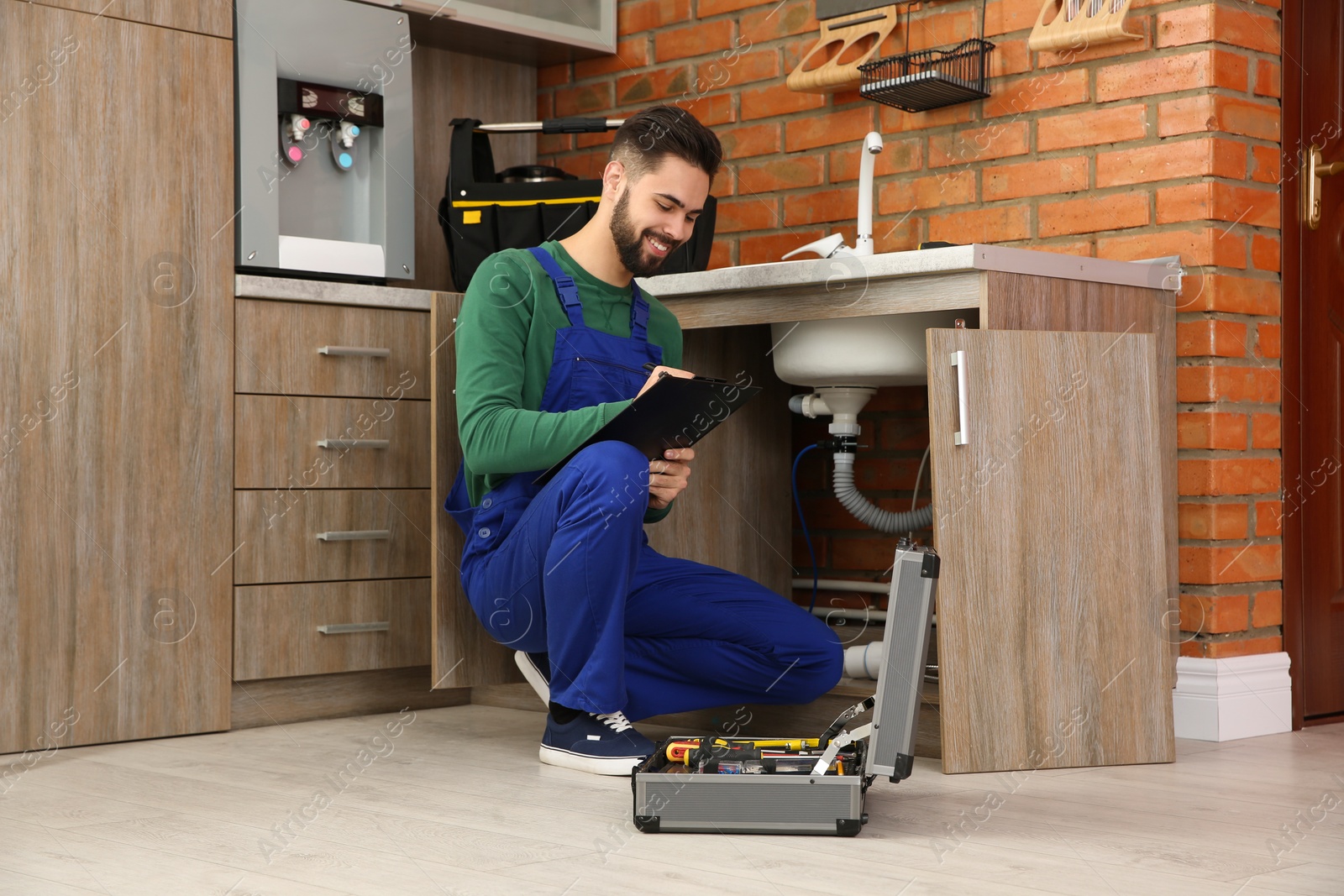 Photo of Male plumber with clipboard near kitchen sink. Repair service