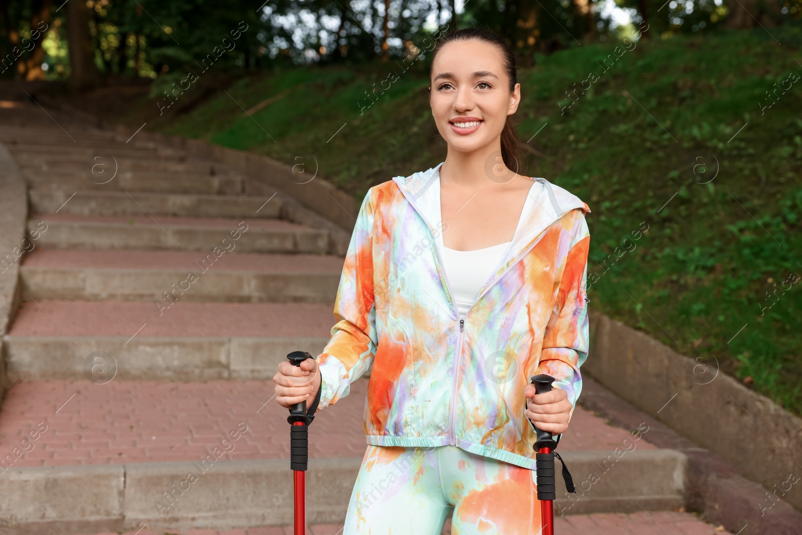 Photo of Young woman practicing Nordic walking with poles on steps outdoors