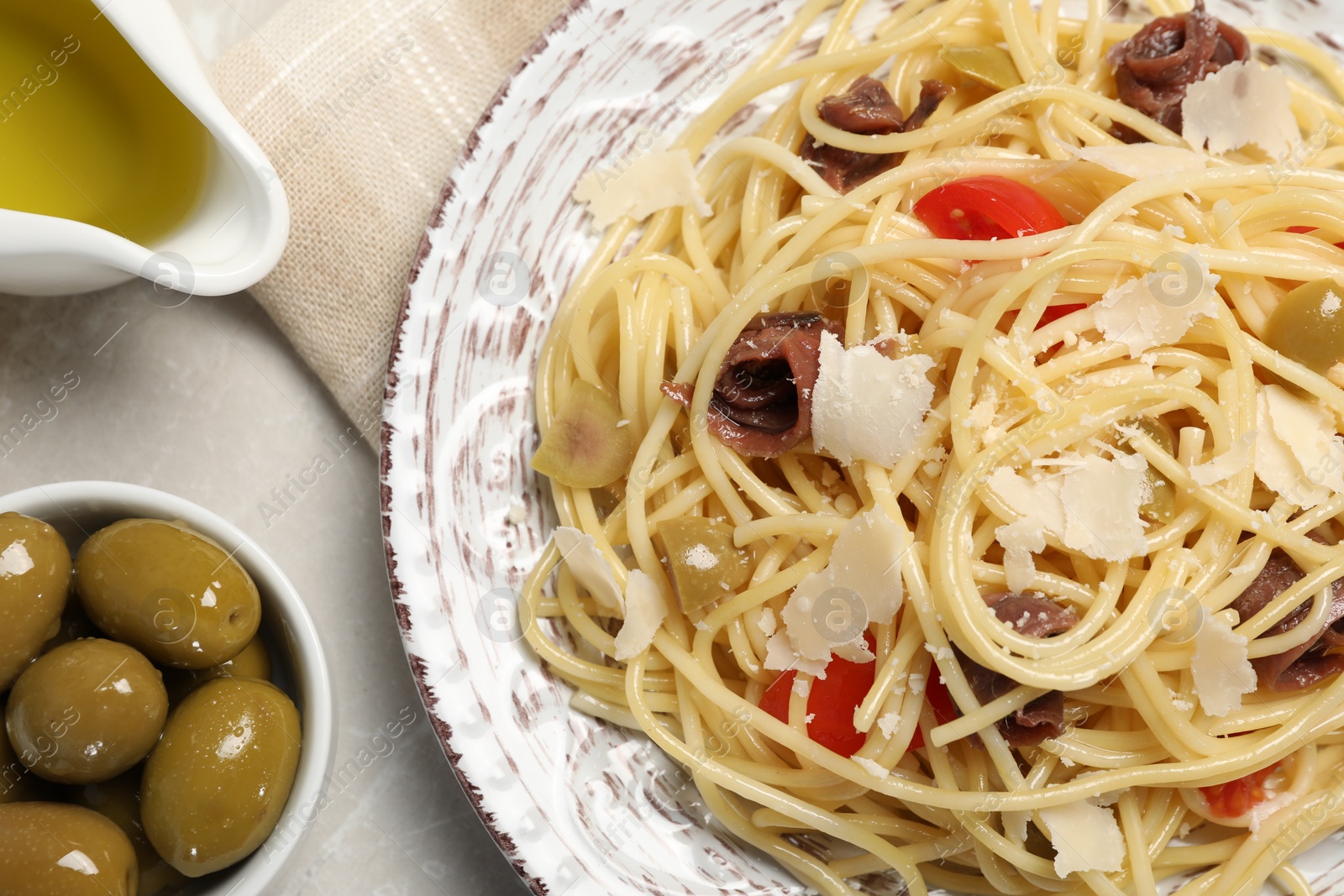 Photo of Delicious pasta with anchovies, tomatoes and parmesan cheese on light grey table, flat lay