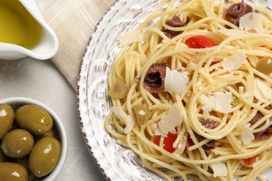 Photo of Delicious pasta with anchovies, tomatoes and parmesan cheese on light grey table, flat lay