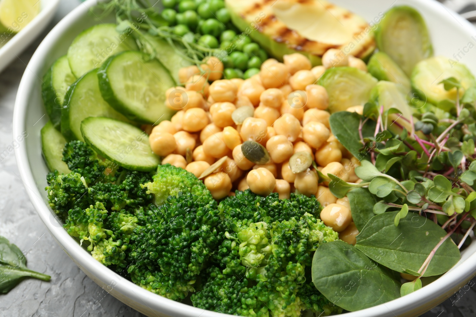 Photo of Healthy meal. Tasty vegetables and chickpeas in bowl on grey table, closeup