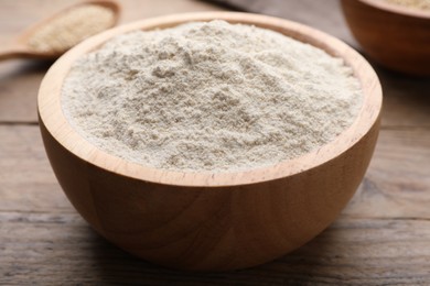 Photo of Quinoa flour in bowl on wooden table, closeup