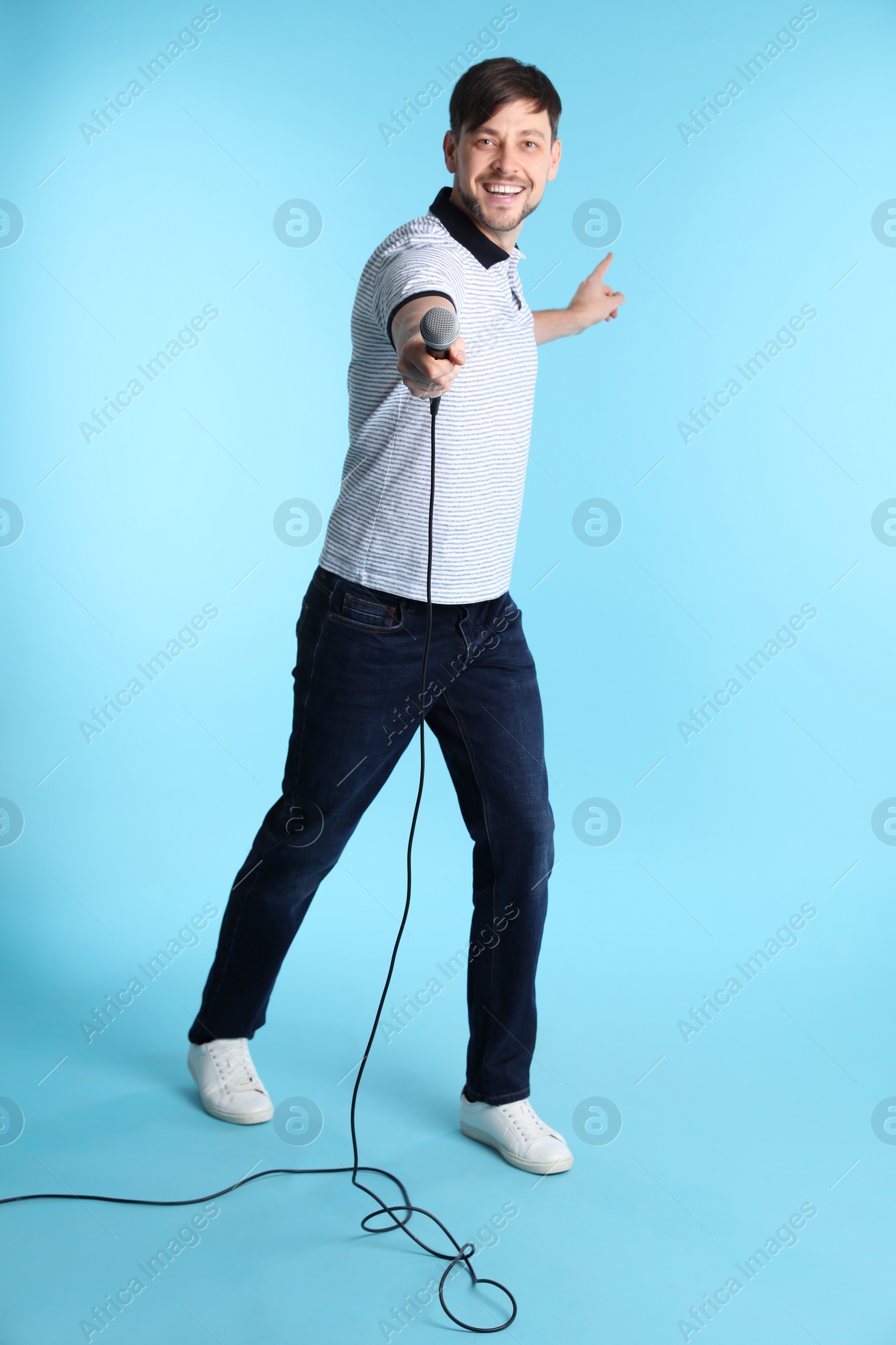 Photo of Handsome man in casual clothes with microphone on color background