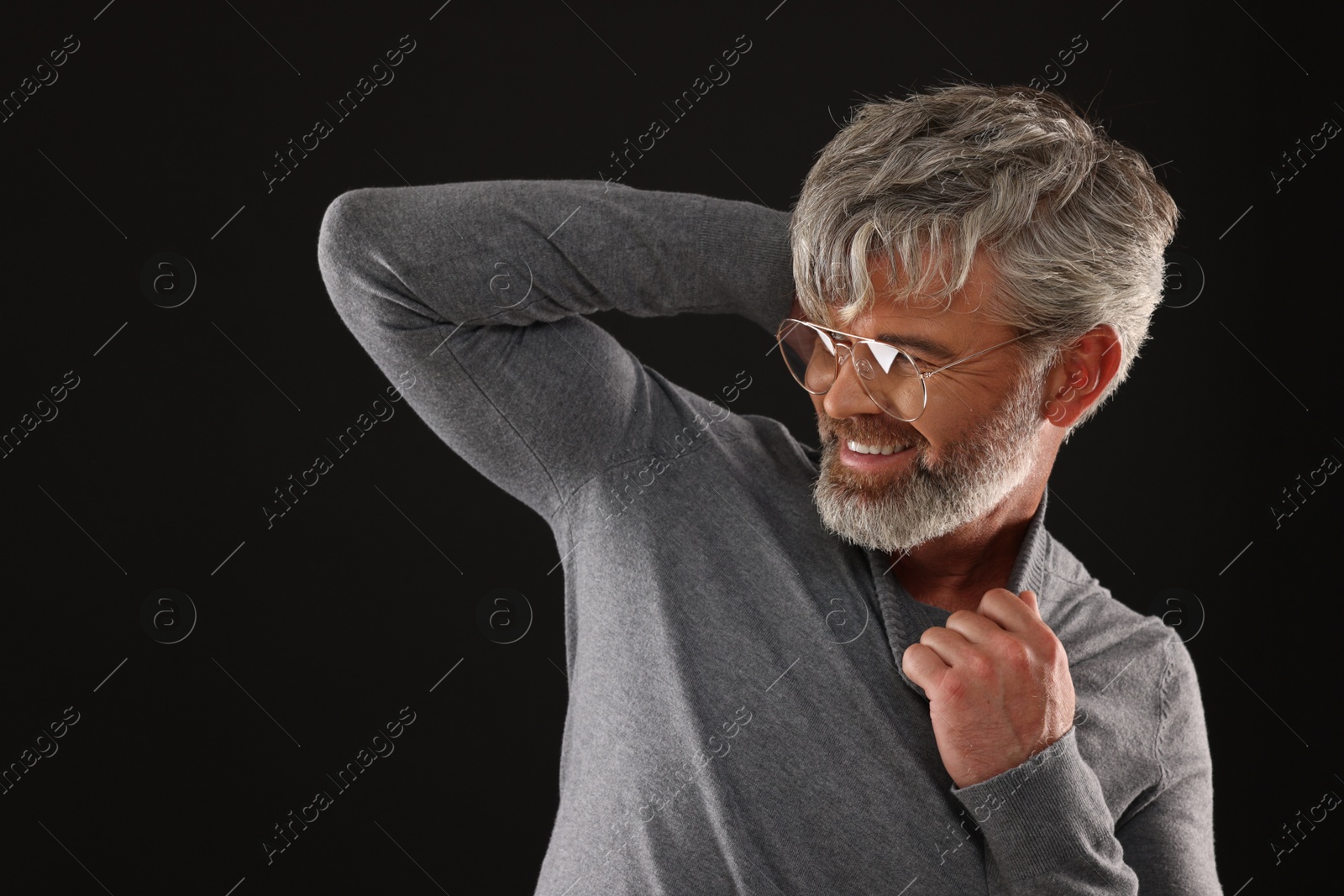 Photo of Portrait of smiling man with beautiful hairstyle on black background. Space for text