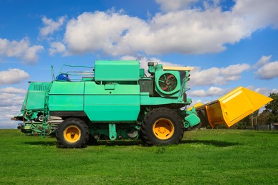 Modern combine harvester on green lawn with fresh grass