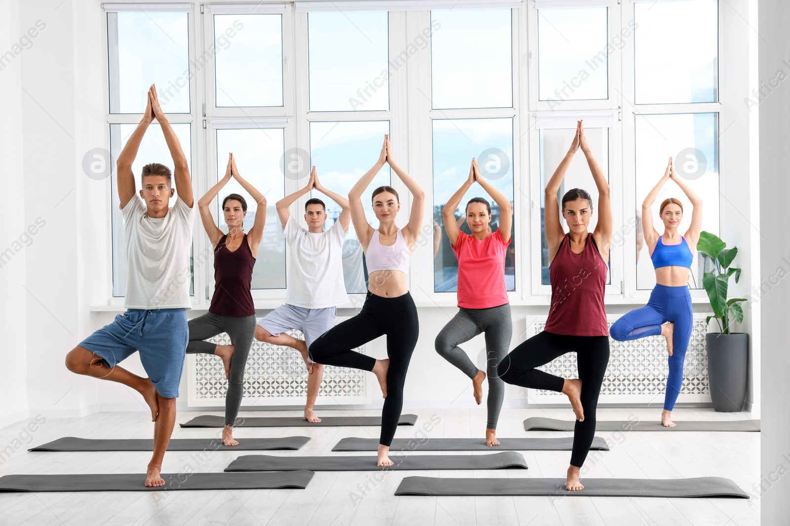 Photo of Group of people practicing yoga on mats indoors