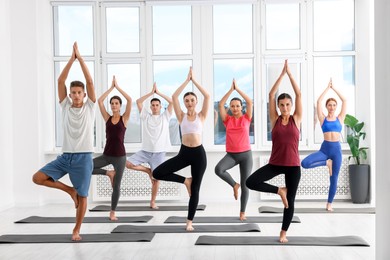 Group of people practicing yoga on mats indoors