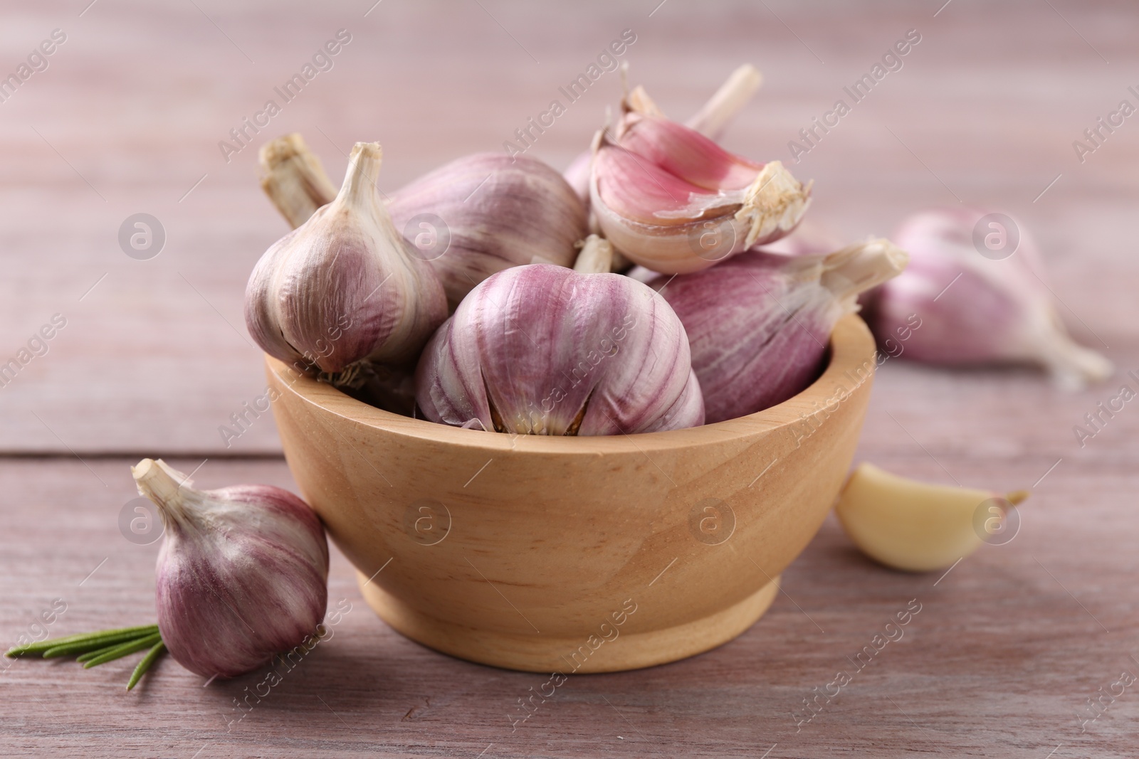 Photo of Bowl with fresh garlic on wooden table, closeup