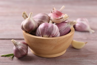 Bowl with fresh garlic on wooden table, closeup