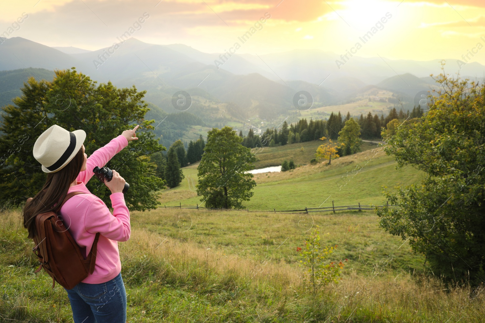 Photo of Young woman with binoculars in mountains, space for text