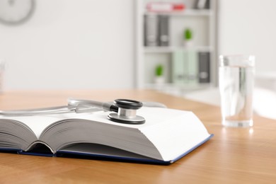 Photo of Book and stethoscope on wooden table in clinic. Space for text
