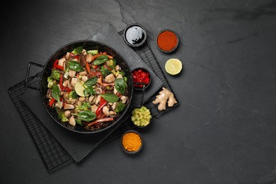 Photo of Stir-fry. Tasty noodles with meat in wok and ingredients on grey textured table, flat lay. Space for text