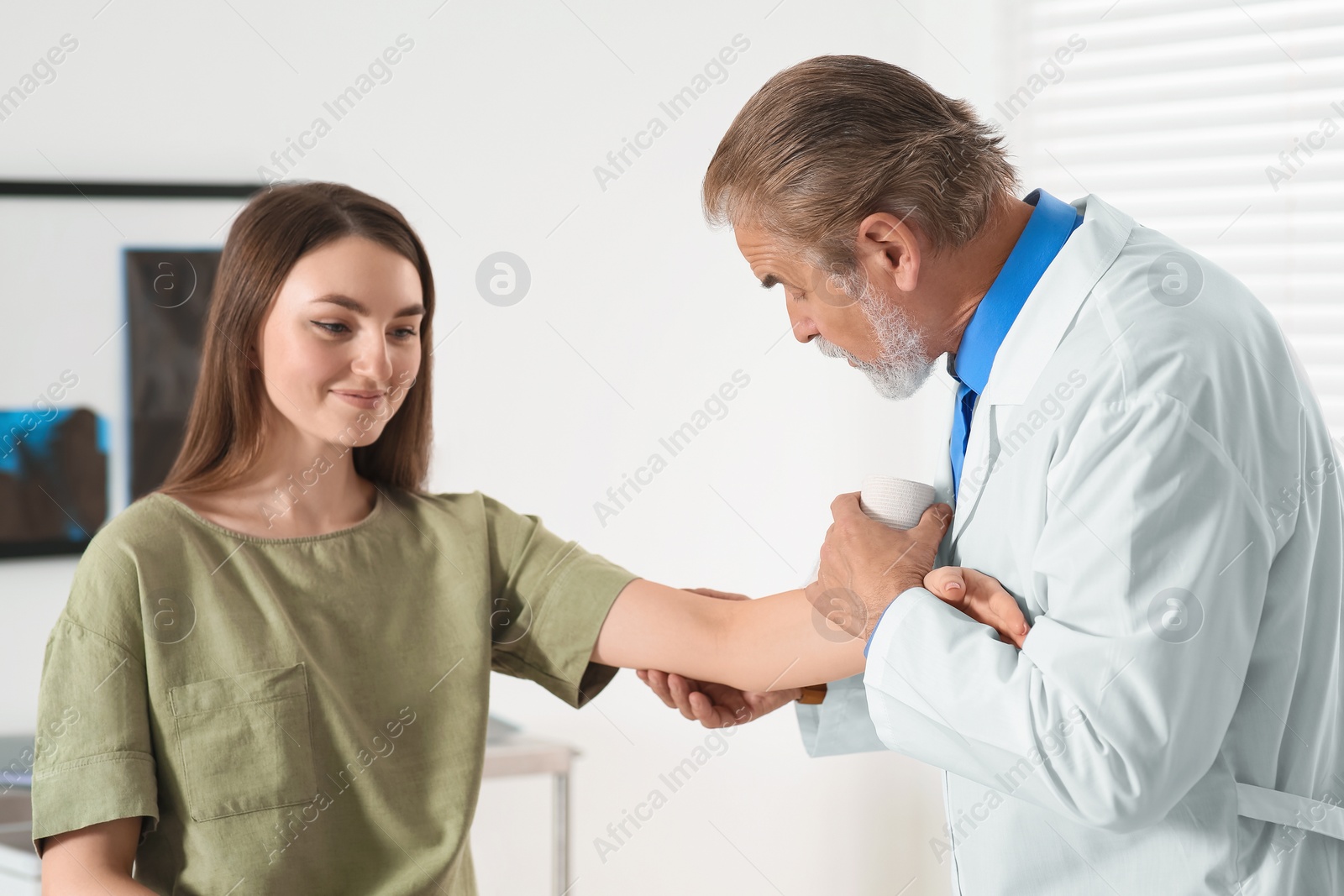 Photo of Orthopedist examining patient with injured arm in clinic