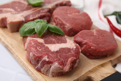 Photo of Cut fresh beef meat with basil leaves on wooden board, closeup