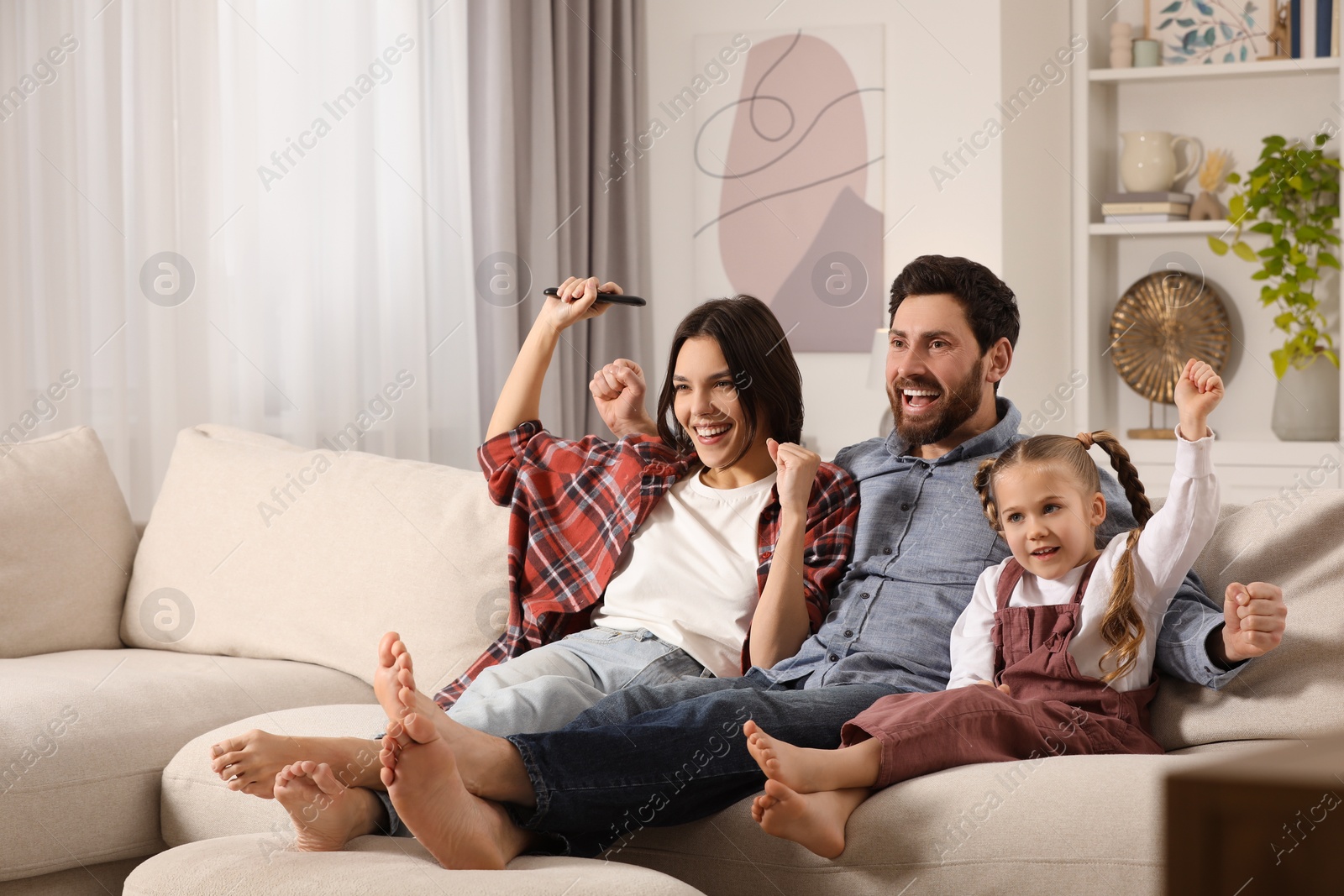 Photo of Happy family watching TV on sofa at home, space for text