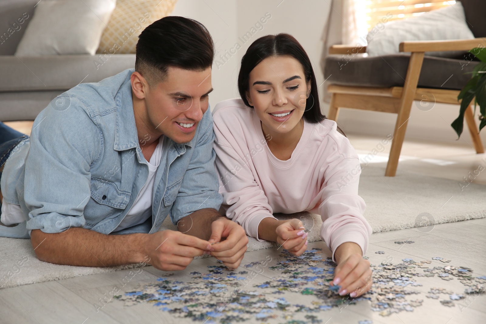 Photo of Happy couple playing with puzzles on floor at home