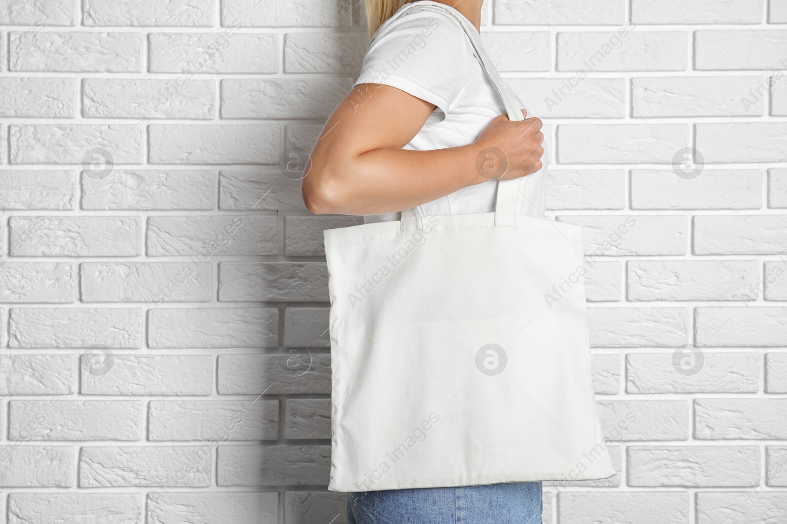 Photo of Woman with tote bag near brick wall. Mock up for design