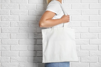 Woman with tote bag near brick wall. Mock up for design