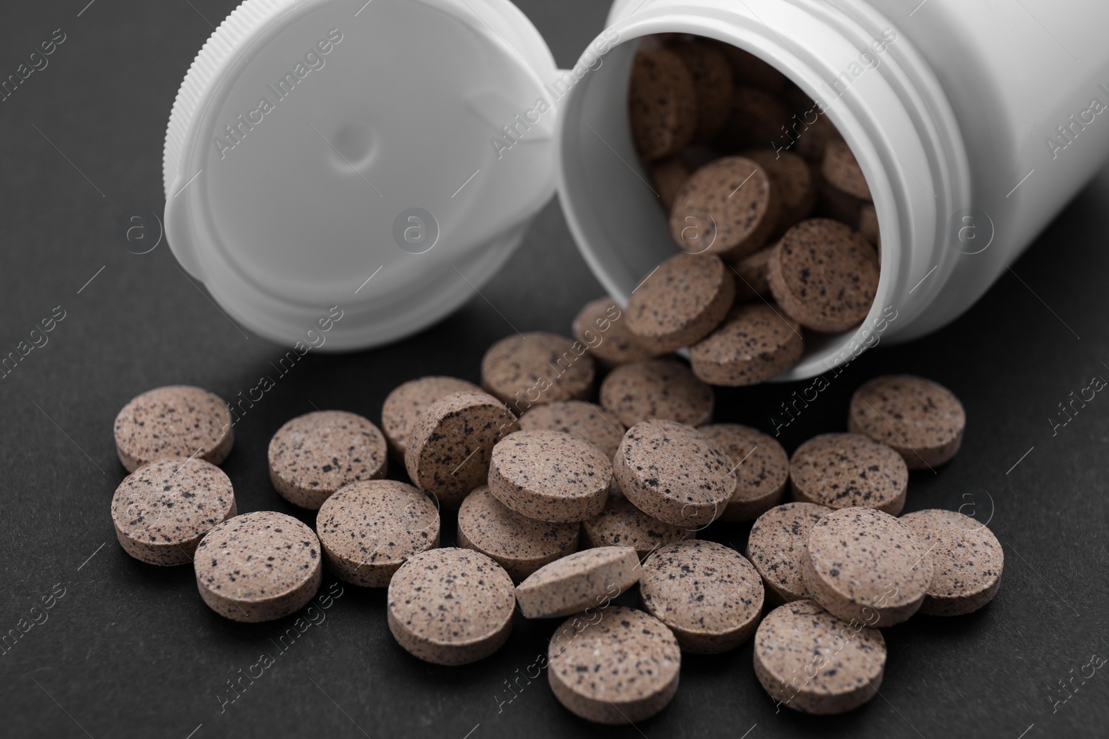 Photo of Jar with brewer`s yeast tablets on black background, closeup