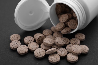 Jar with brewer`s yeast tablets on black background, closeup