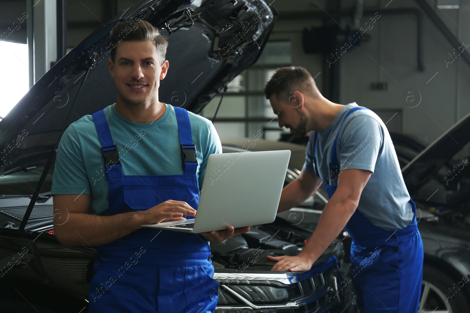 Photo of Mechanic with laptop doing car diagnostic at automobile repair shop