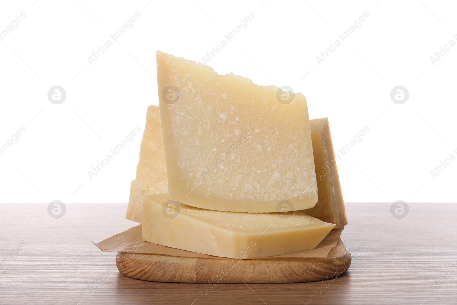 Photo of Pieces of delicious parmesan cheese on wooden table against white background