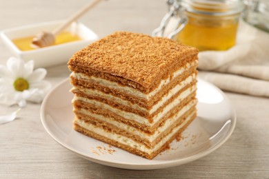 Photo of Slice of delicious layered honey cake served on wooden table, closeup