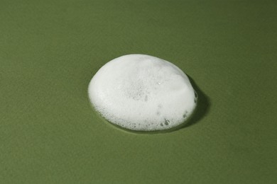 Photo of Sample of cleansing foam on dark green background, closeup. Cosmetic product