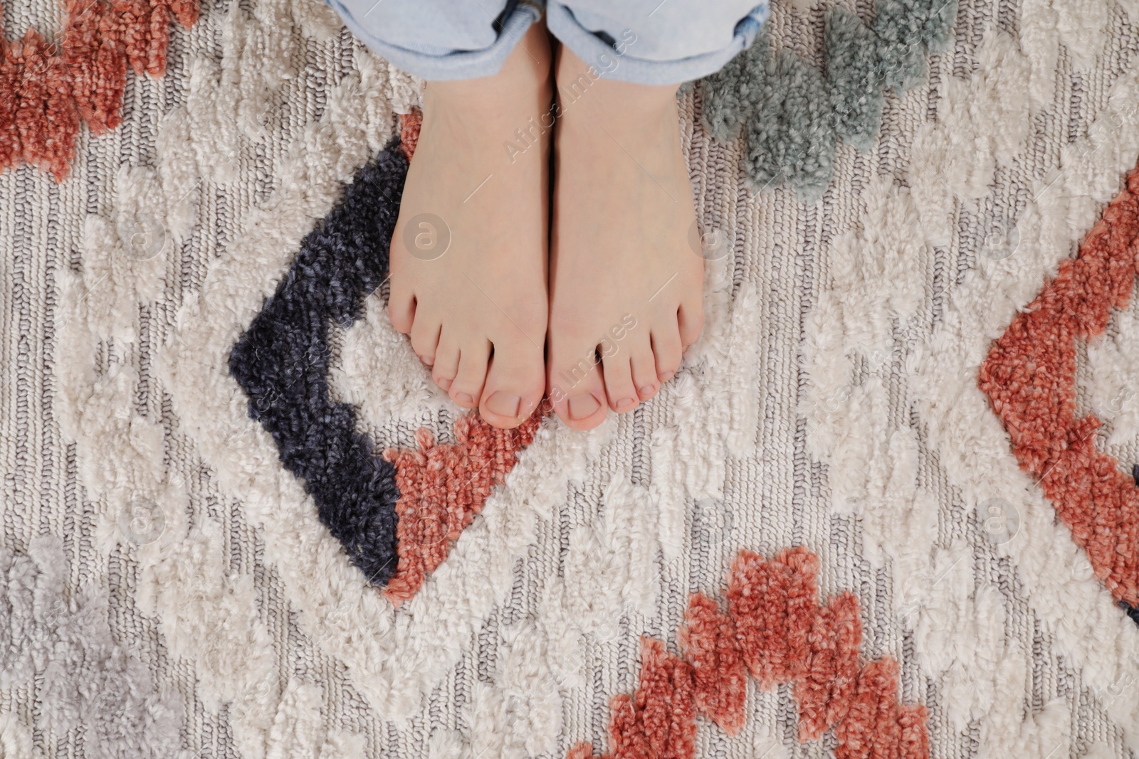 Photo of Woman standing on carpet with pattern at home, top view