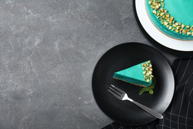 Photo of Delicious homemade spirulina cheesecake served on grey table, top view. Space for text