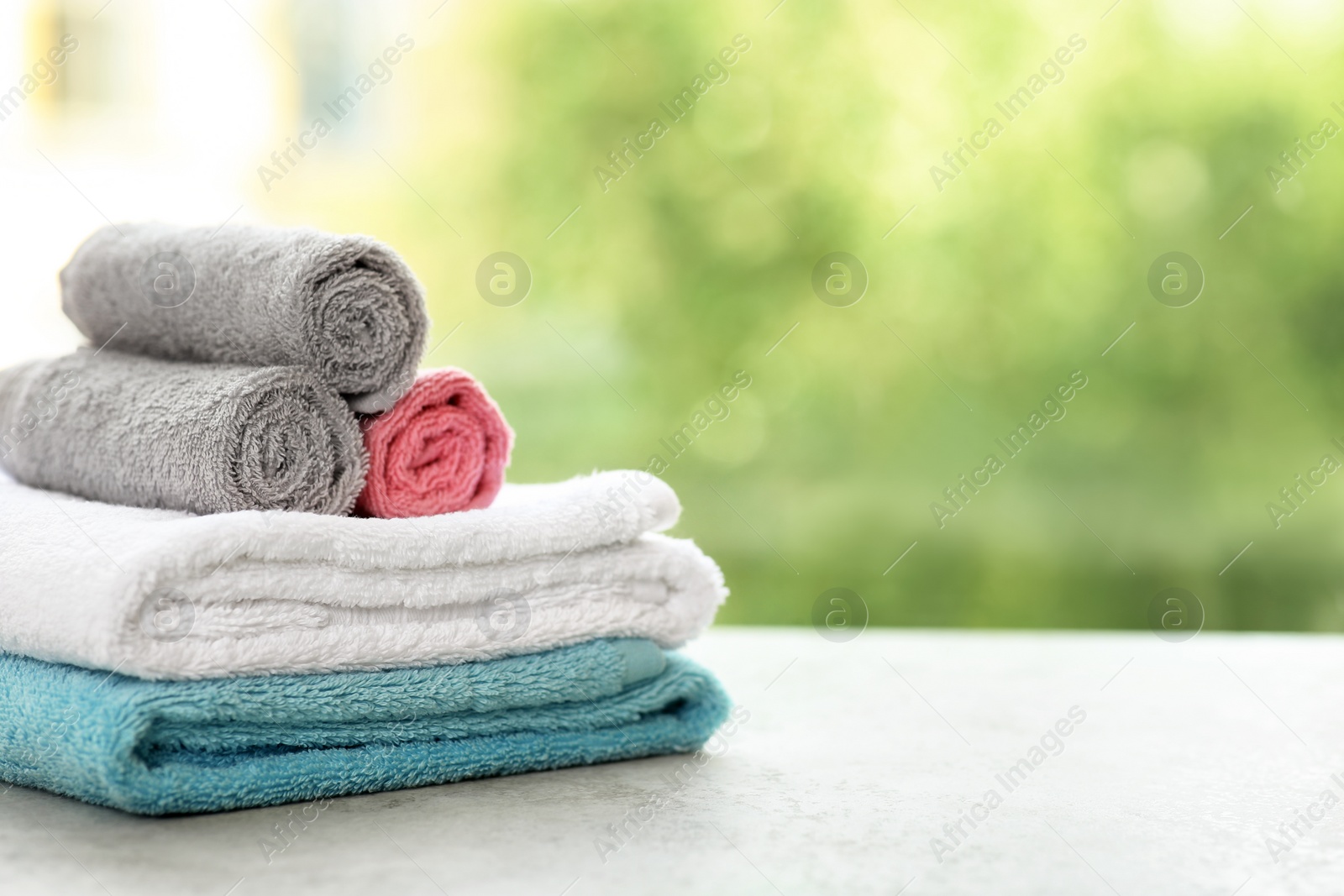 Photo of Stack of clean towels on table against blurred background. Space for text