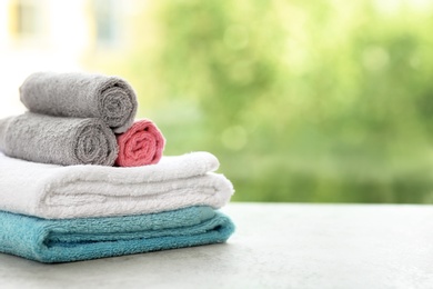 Stack of clean towels on table against blurred background. Space for text