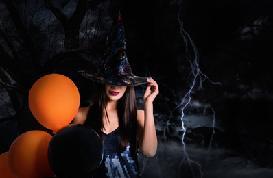 Witch with balloons and dark forest on Halloween
