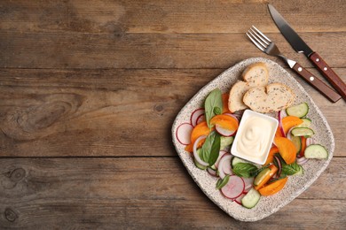 Photo of Plate of delicious vegetable salad with mayonnaise and croutons served on wooden table, flat lay. Space for text